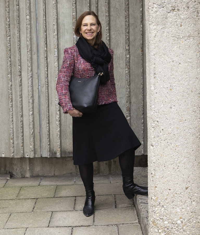 Annette Roeckl showcases the black Diana bag, a timeless shoulder bag, dressed in an elegant manner.