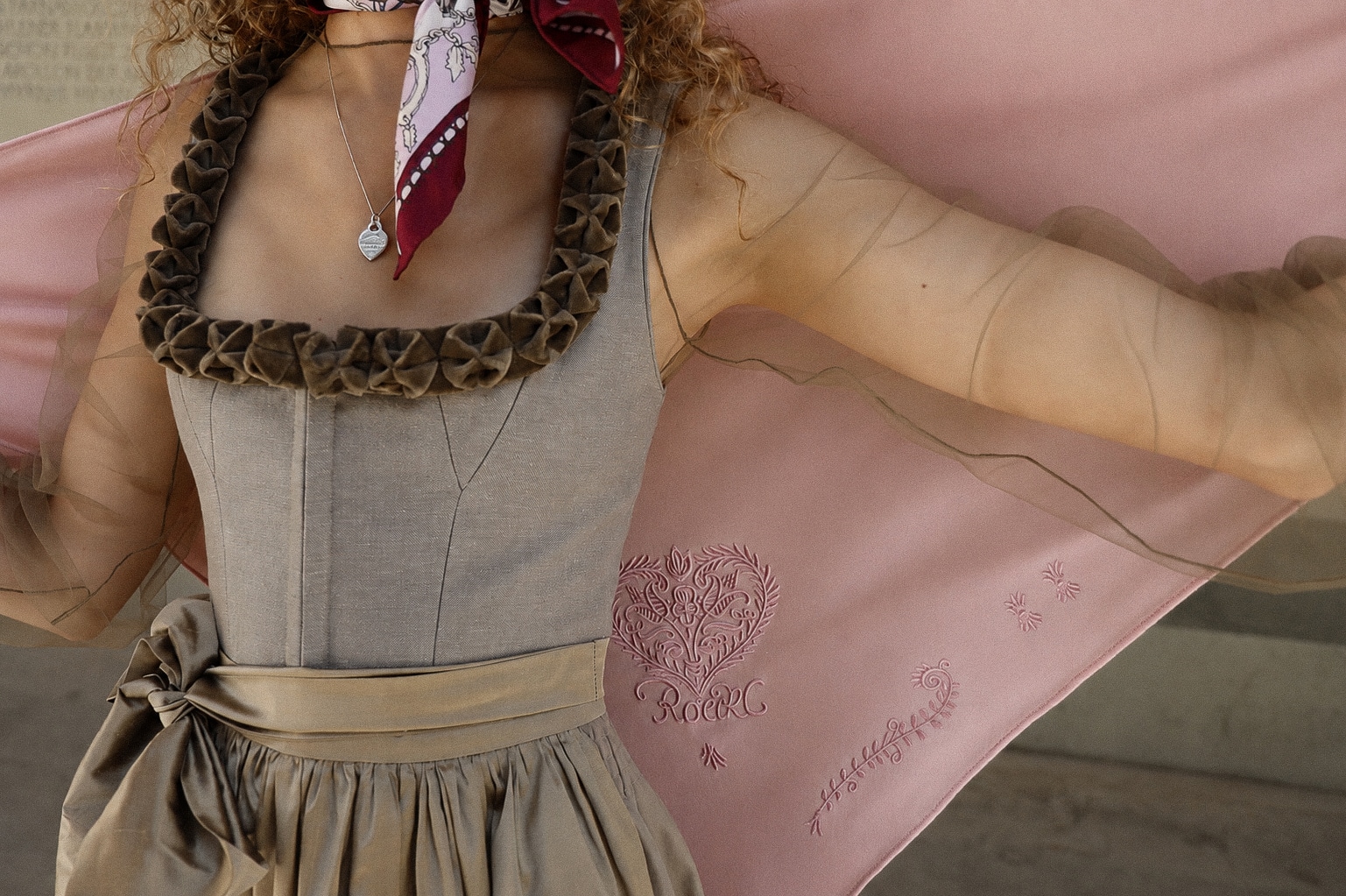 Detailaufnahme einer beigefarbenen ROECKL-Tasche aus Wildleder mit gesticktem Herzmotiv – elegantes Accessoire zur Tracht.
