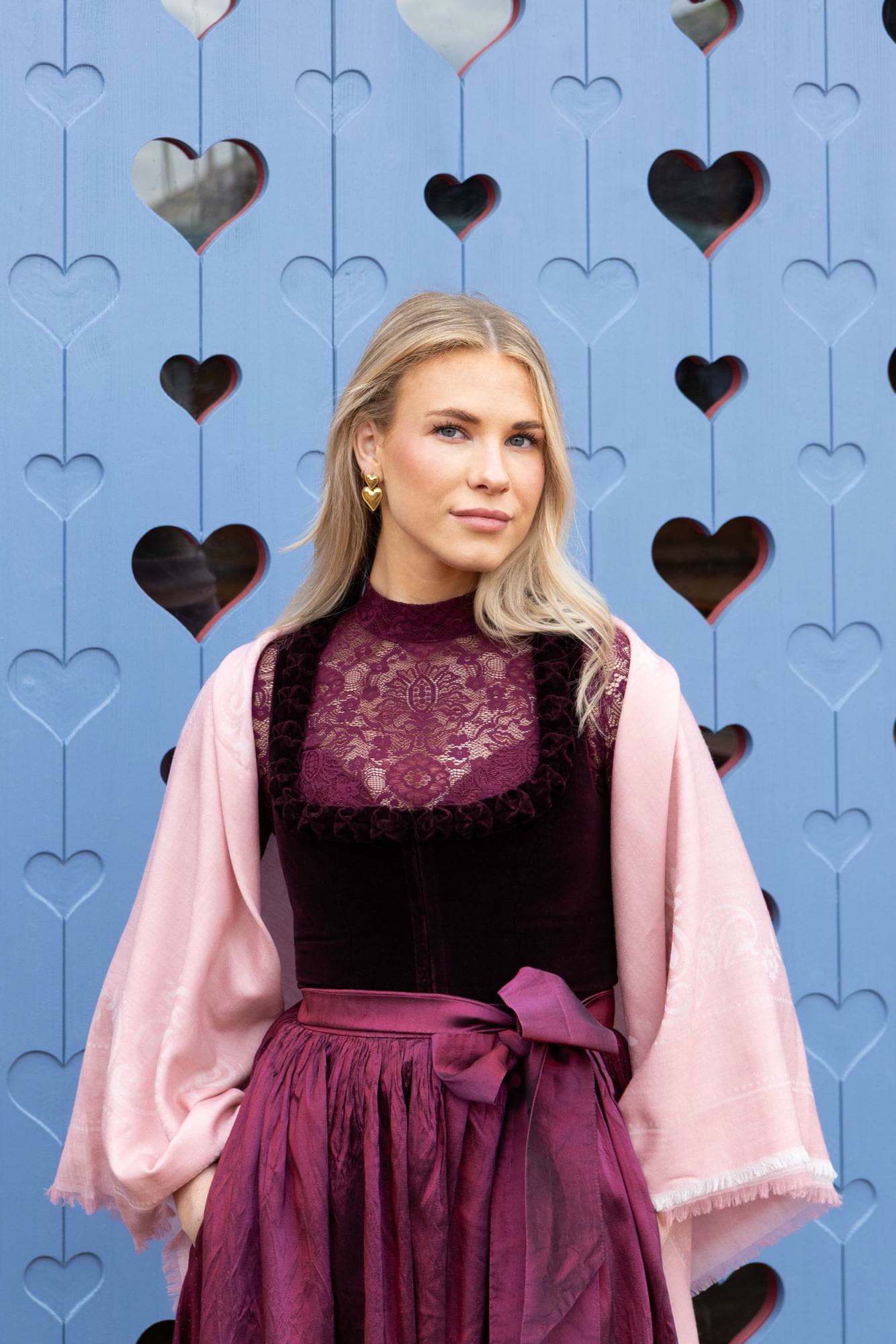 Frau im Samtdirndl in Beerentönen mit rosa ROECKL-Schal – feminines Styling mit edlen Trachten-Accessoires.