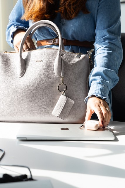 Businessfrau mit grauer ROECKL-Ledertasche auf Schreibtisch – stilvolle und funktionale Handtasche für den modernen Arbeitsalltag.