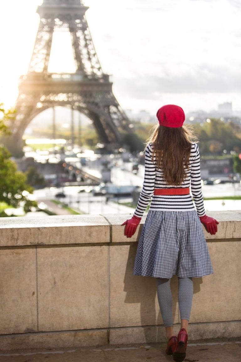 Frau mit roten HandFrau mit roter Baskenmütze und roten Lederhandschuhen vor dem Eiffelturm – französisch inspirierter ROECKL-Look mit eleganten Accessoires.schuhe vor dem Eiffelturm in Paris