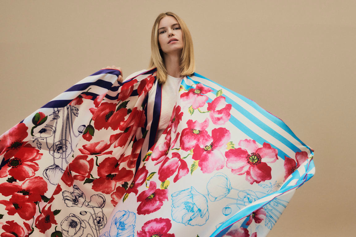 Frau trägt großformatige, farbenfrohe ROECKL-Seidentücher mit Blumen- und Streifendessin – luxuriöse Tücher für elegante Looks.