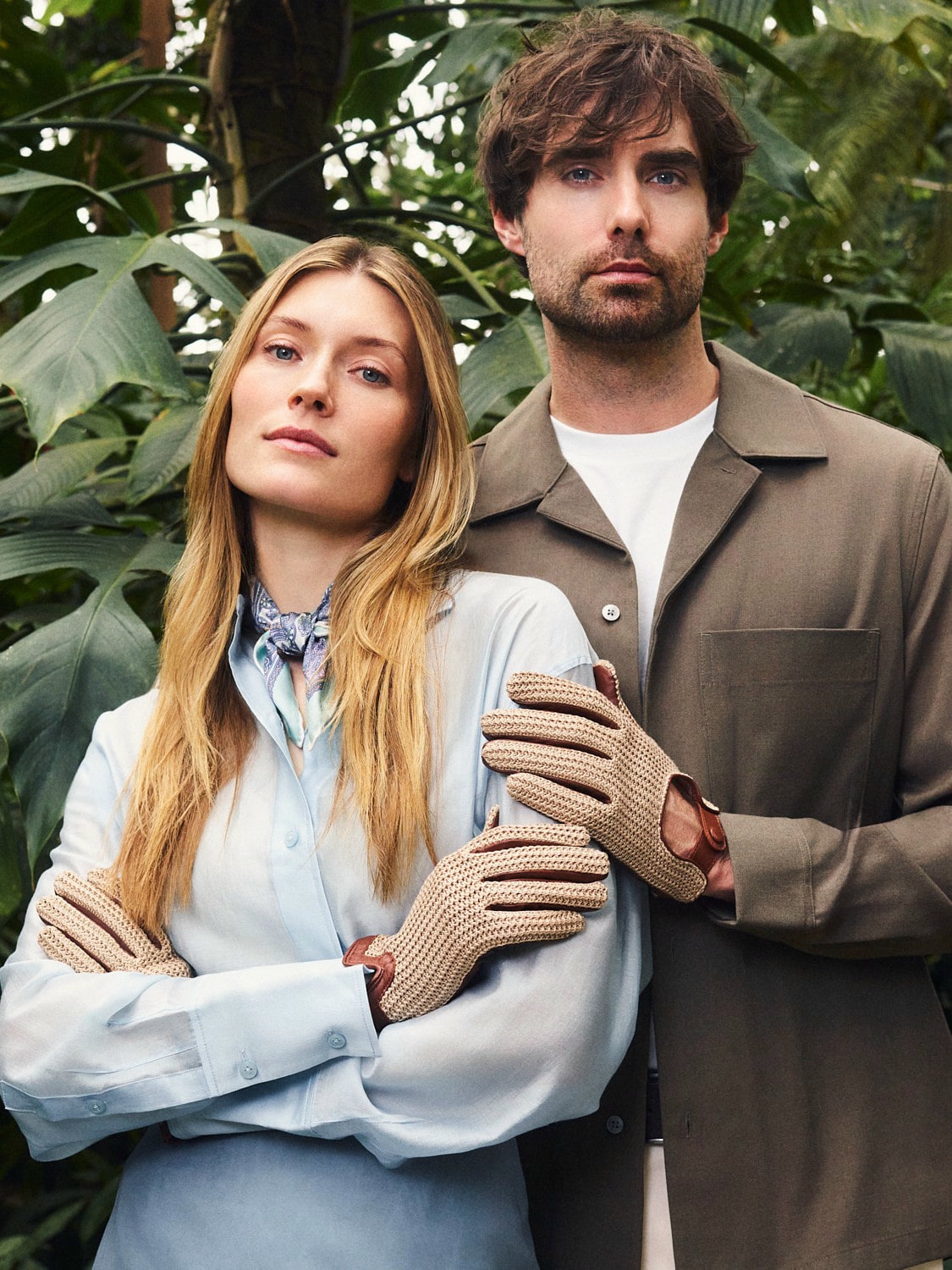 Elegantes Paar mit Leder- und Häkelhandschuhen von ROECKL vor tropischer Pflanzenkulisse