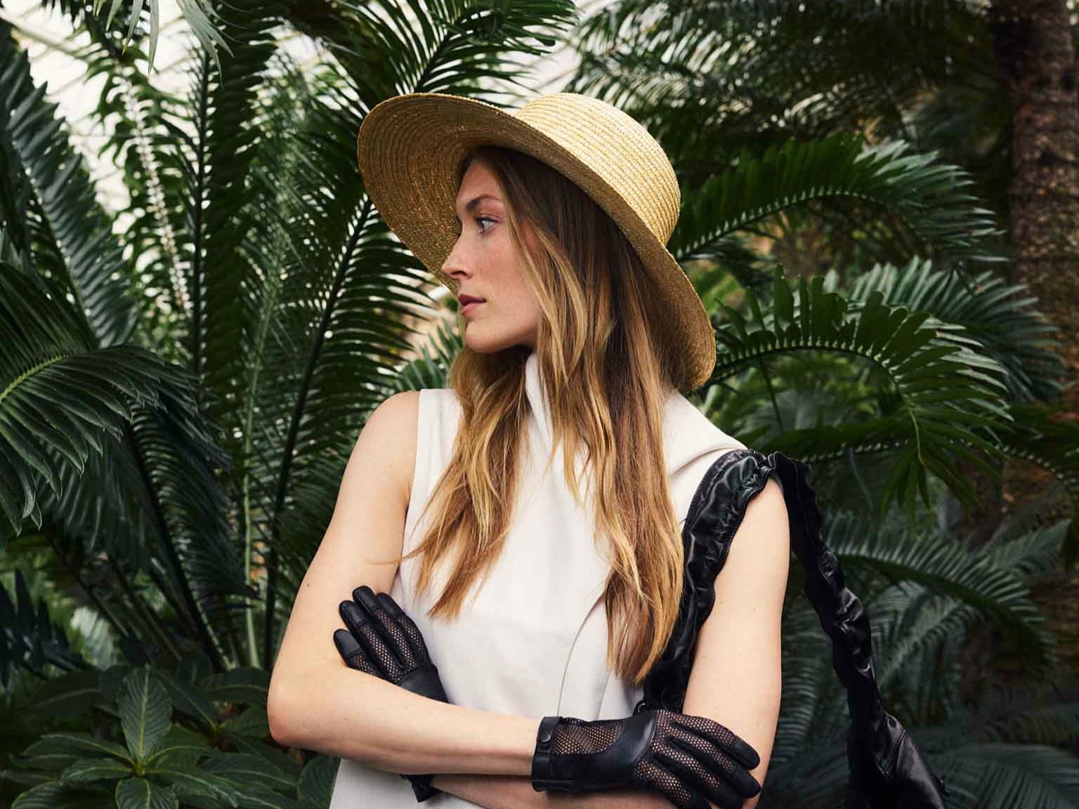 Frau trägt leuchtend roten ROECKL-Strohhut mit breiter Krempe – luxuriöser Statement-Hut aus feinem Geflecht für sonnige Tage.