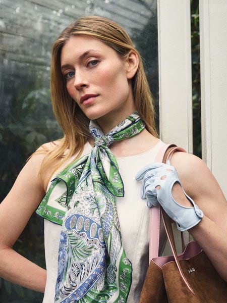 Frau mit grün gemustertem ROECKL Seidenschal, hellblauen Fingerless-Lederhandschuhen und ROECKL Handtasche