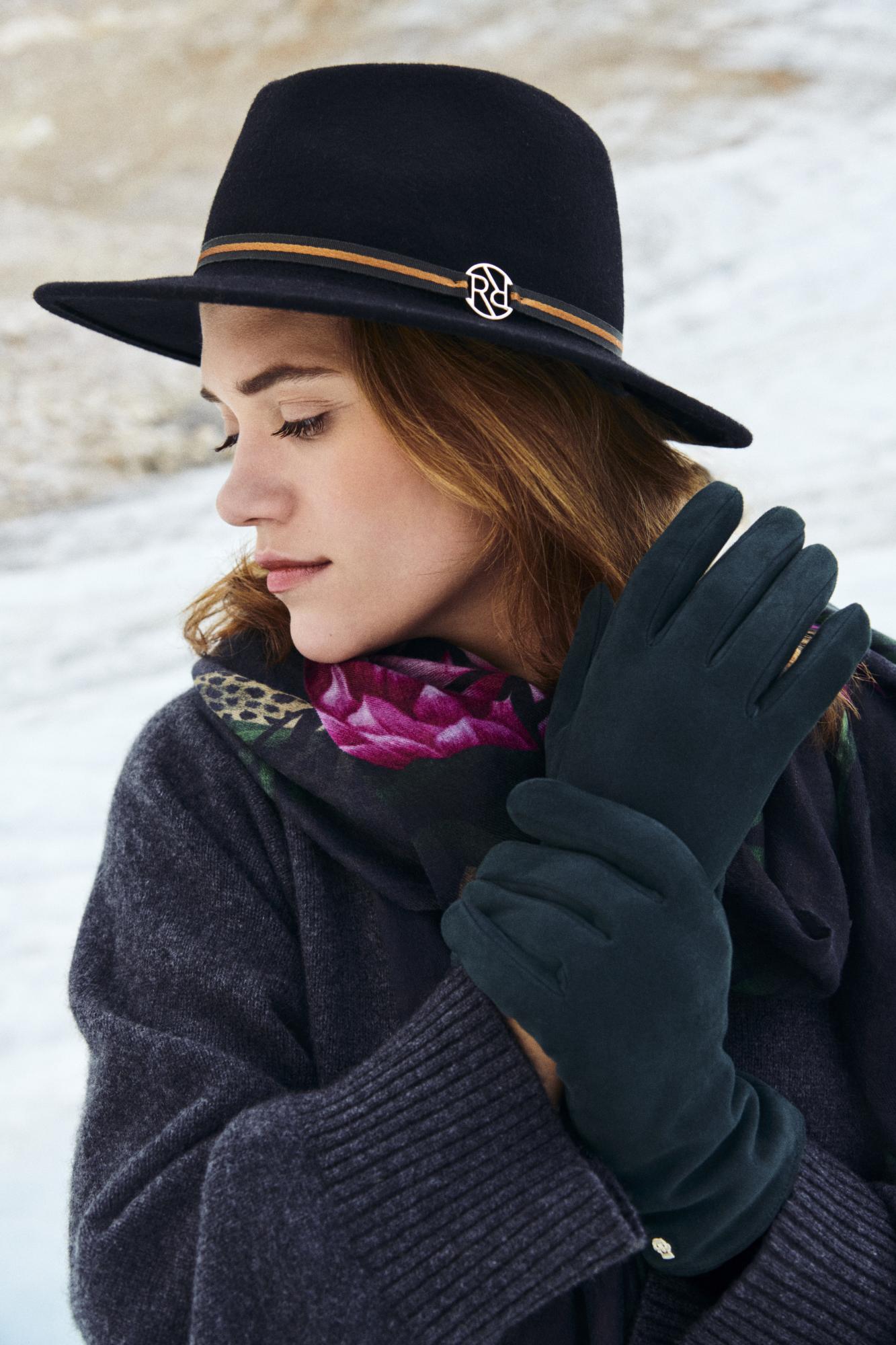 Elegante Frau mit schwarzem ROECKL-Hut, dunkelgrünen Wildlederhandschuhen und floralem Schal – stilvolles Winteraccessoire-Ensemble für zeitlose Eleganz.