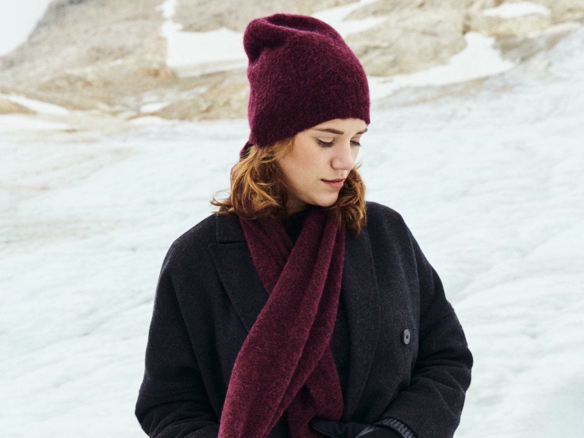 Eine junge blonde Dame trägt hochwertige Kurzfinger-Autofahrerhandschuhe aus hellem Peccary Leder.