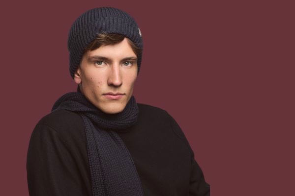 Herr in Mantel trägt einen gemusterten Schal und eine graue Schiebermütze.