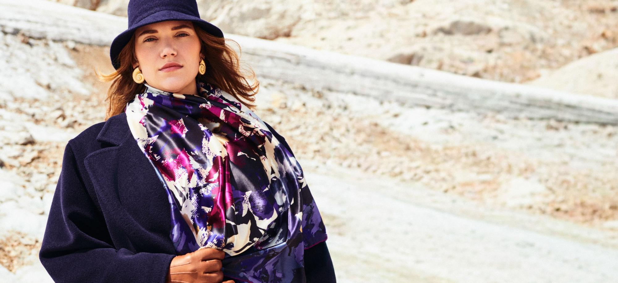 Frau mit dunkelblauem Mantel, passendem Hut und farbenprächtigem ROECKL-Seidentuch – luxuriöses Accessoire für stilvolle Herbst-Looks.