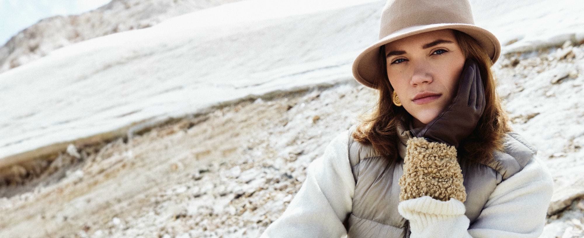 Eine blonde Frau mit schulterlangem Haar trägt ein großes, buntes Seidentuch mit roten Mohnblumen, blauen Streifen und floralen Skizzen.