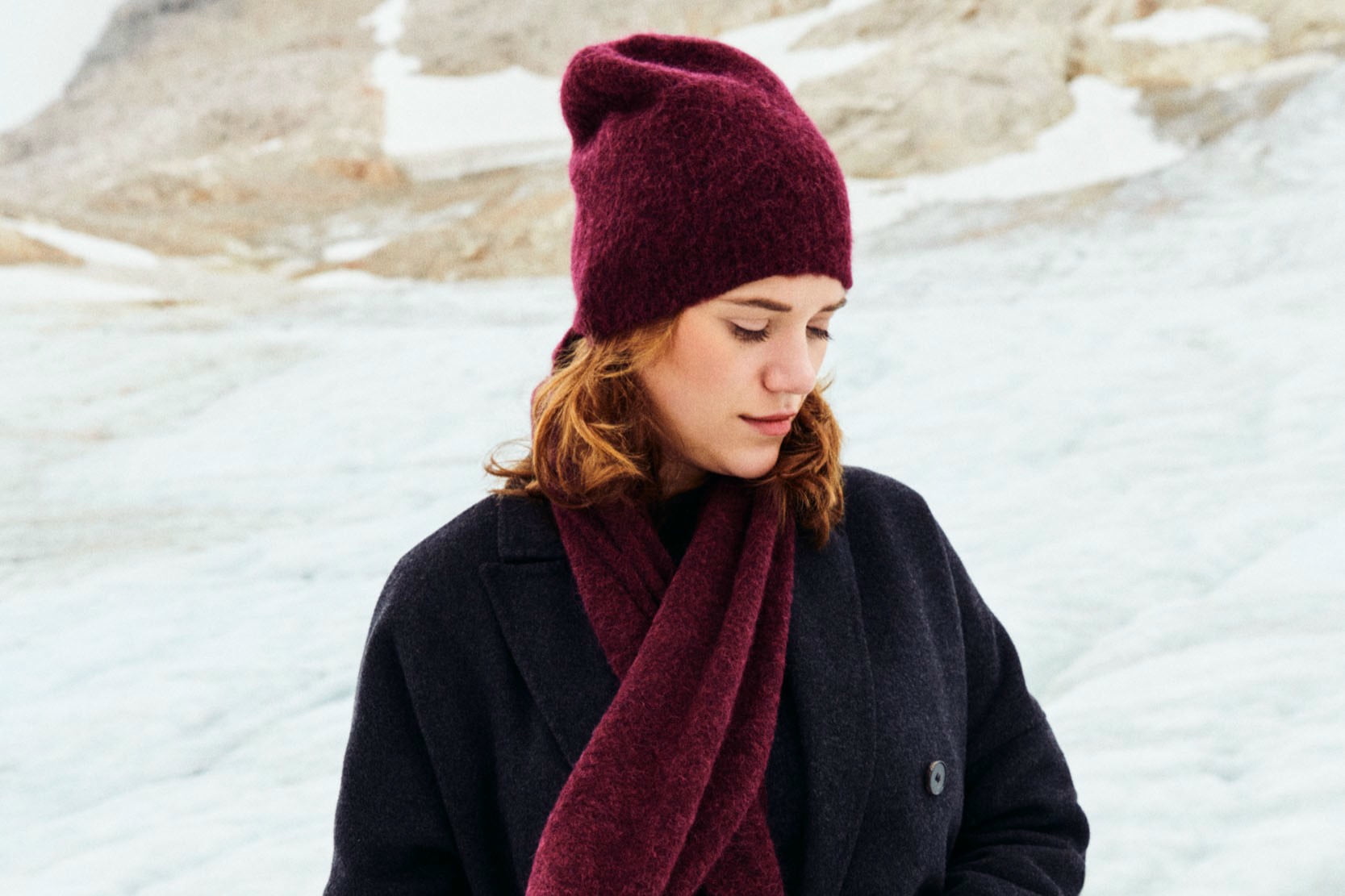 Eine lachende Dame trägt mehrere bunte Strickschals um ihren Hals.