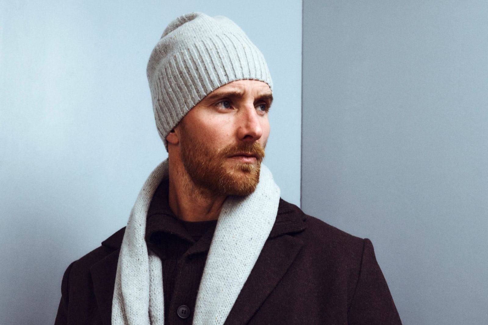 Mann mit Strickmütze, Schal und Mantel von ROECKL – hochwertige Winteraccessoires aus feiner Wolle.