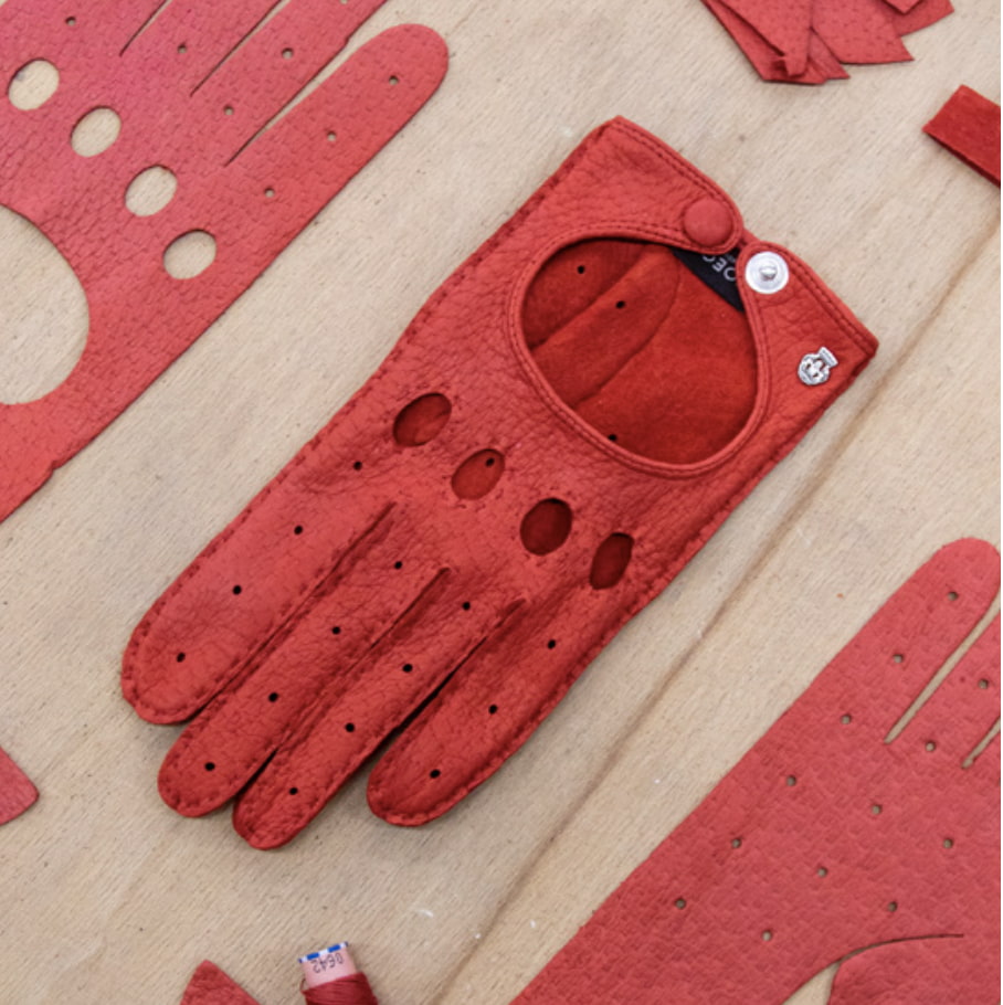 Ein fertiger, roter Autofahrerhandschuh aus Peccary Leder und seine Ausschnitte