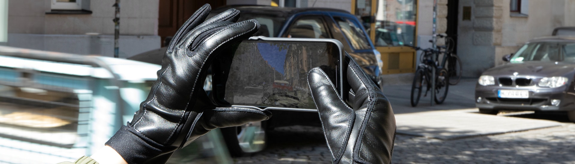 Person trägt schwarze ROECKL-Lederhandschuhe mit Touchscreen-Funktion und fotografiert mit dem Smartphone – elegante Funktionalität für unterwegs.