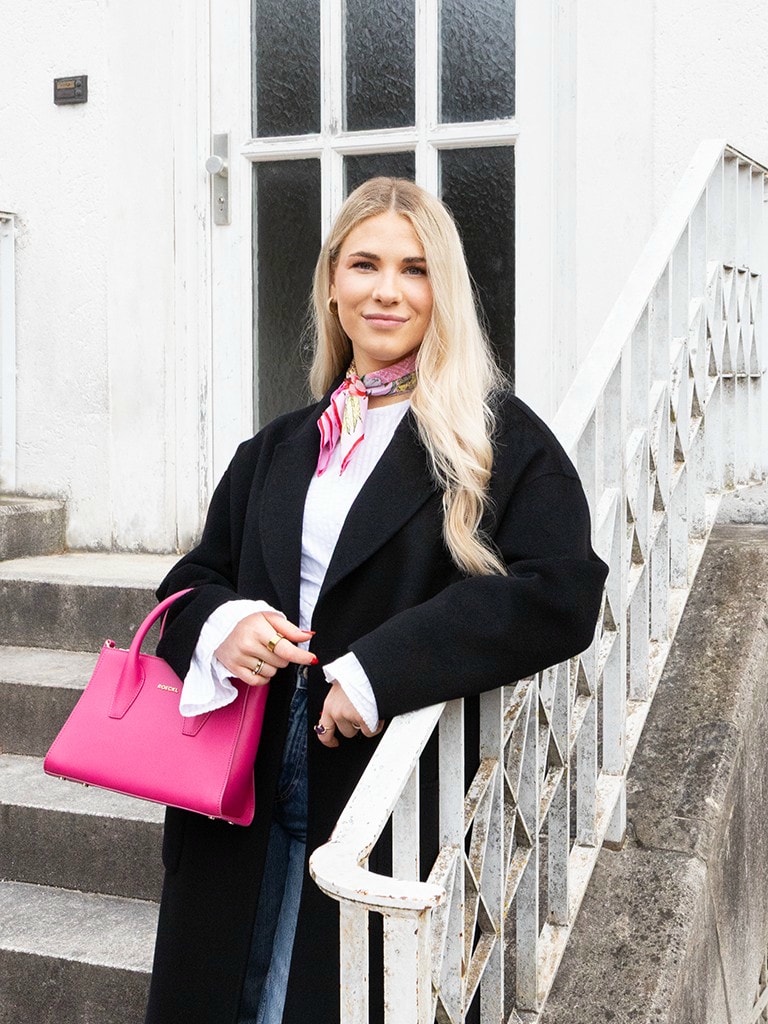Frau mit pinker ROECKL-Handtasche und farbenfrohem Seidentuch – moderner Business-Look mit eleganten Leder-Accessoires.