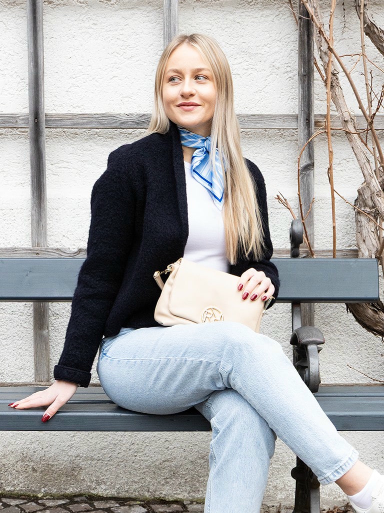 Frau mit beiger ROECKL-Ledertasche und hellblauem Seidentuch – eleganter Alltagslook mit hochwertigen Accessoires aus Leder und Seide.