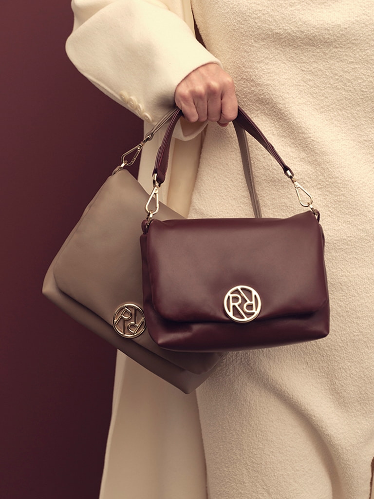 The Roeckl Women\'s Handbag Soho Crossover in burgundy and beige with modern Roeckl logo are buttery soft and are perfect companions for autumn and winter.